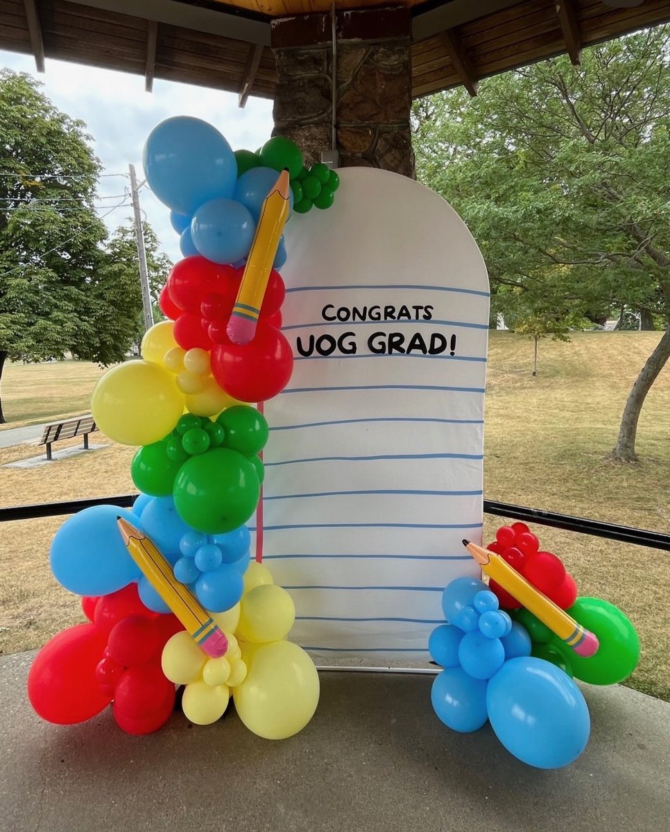 Primary colour garland with pencil balloons on a notebook paper arch reading Congrats grad